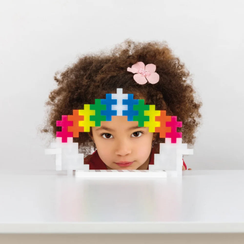 A single 50mm Plus-Plus BIG piece held in a small child's hand to show its chunky size