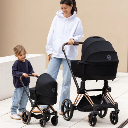 Child pushing a Corolle baby doll in the black Corolle x Cybex 3-in-1 doll pram, just like a real parent