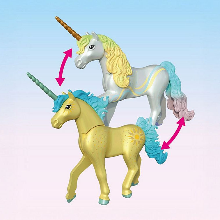 Two unicorn figurines, one white with a blue mane and horn, and the other yellow with a green horn, on a light pink background.