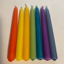Seven colorful taper candles in a rainbow sequence of orange, yellow, green, blue, and purple