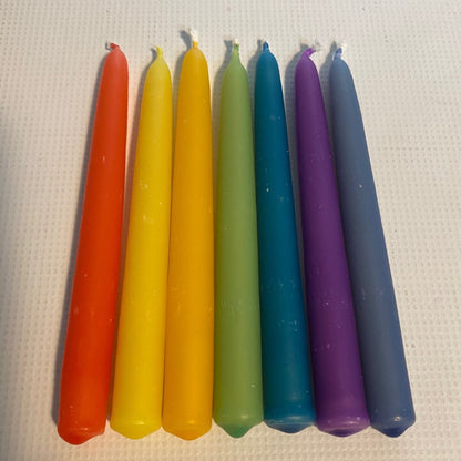 Seven colorful taper candles in a rainbow sequence of orange, yellow, green, blue, and purple